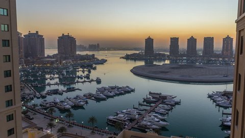 Evening at the Pearl-Qatar day to night timelapse from top. It is an artificial island in Qatar. View of the Marina and residential buildings in Porto Arabia in Doha, Qatar, Middle East