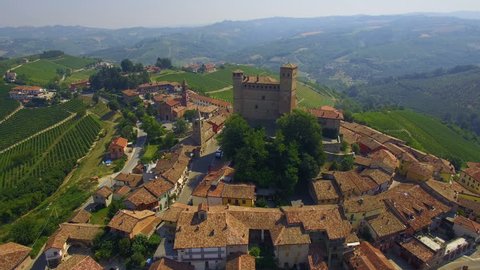 Aerial: slow flight over small Italian town - Serralunga d'Alba surrounded with vineyard hills. Piedmont region, Italy.