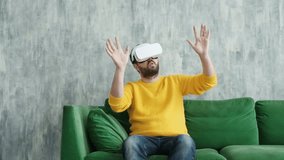 Man using virtual reality headset at home. Future is now. Handsome man playing game in vr glasses. Man touch something using modern virtual reality glasses