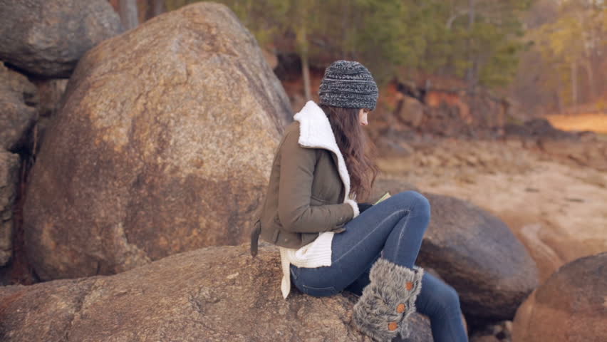 Woman climbs over rocks at the lake.