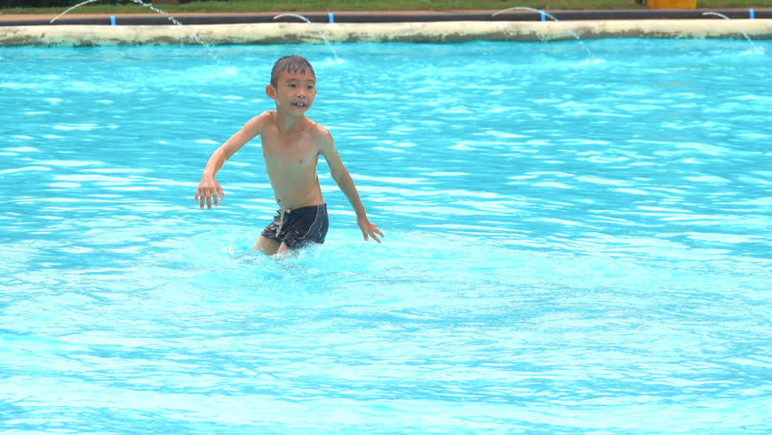 Swimming on summer concept. Asian children boy swim and play in swimming pool in holiday. Water pond is blue clean and clear for safety child to play and water level is not deep. Boy is happy holiday