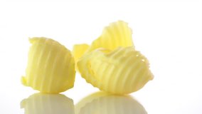 Fresh Butter curls rotated on a white background. Pieces of butter rotating on white, studio shot. 4K UHD video