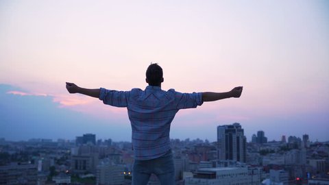 Man throwing his hands on roof edge, enjoying freedom, believe future success. Confident male enjoying city sunrise, achievement and inspiration. Happy tourist on skyscraper top, victory and purpose
