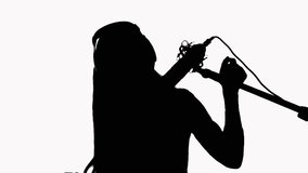 Silhouette of a young girl who sings in a studio microphone. On a white background.