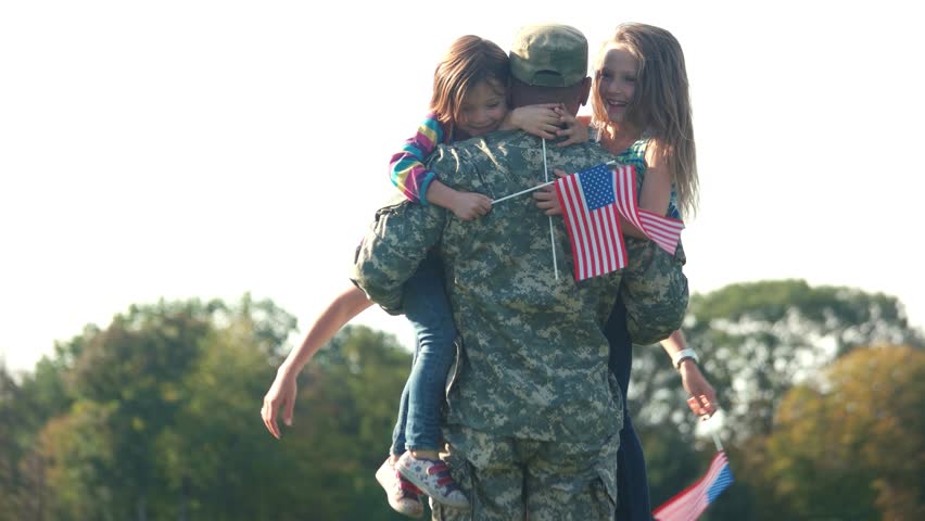 Two adorable little girls with usa backgrounds hug their father. Embracing arrived daddy, meet a hero in the park.