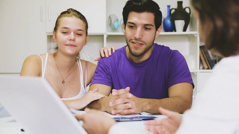 Young smiling couple consulting with female real estate agent in home interior 