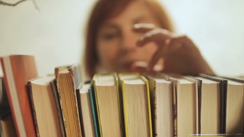young woman choose books on shelf