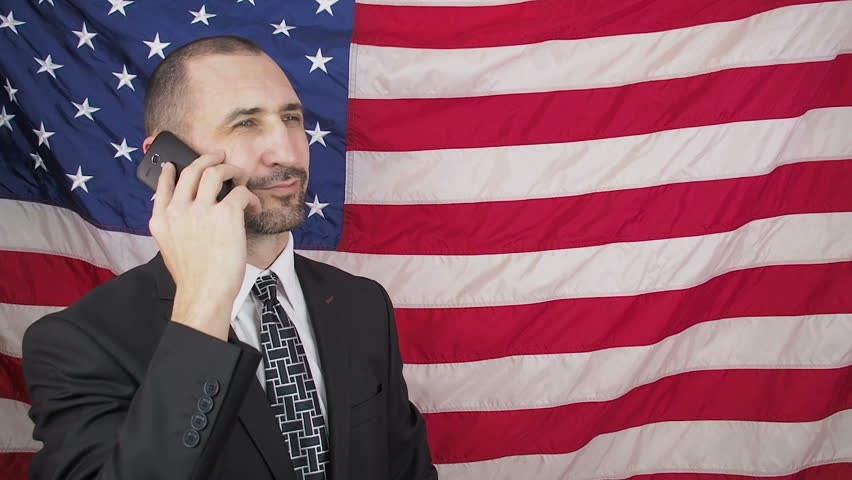 American businessman talking on the phone. Man with phone on a background of a flag of America.