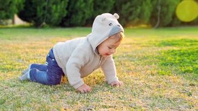 Cute little baby crawling outdoors, sweet baby boy discovering environment, having fun on fresh green grass field in the park, slow motion. Full HD Video 1920x1080