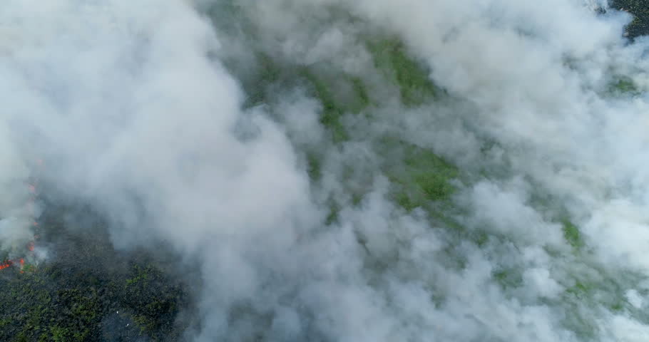 Thick white smoke filling the frame as green grass hill burns aerial drone shot 4K | Shutterstock HD Video #1007402593