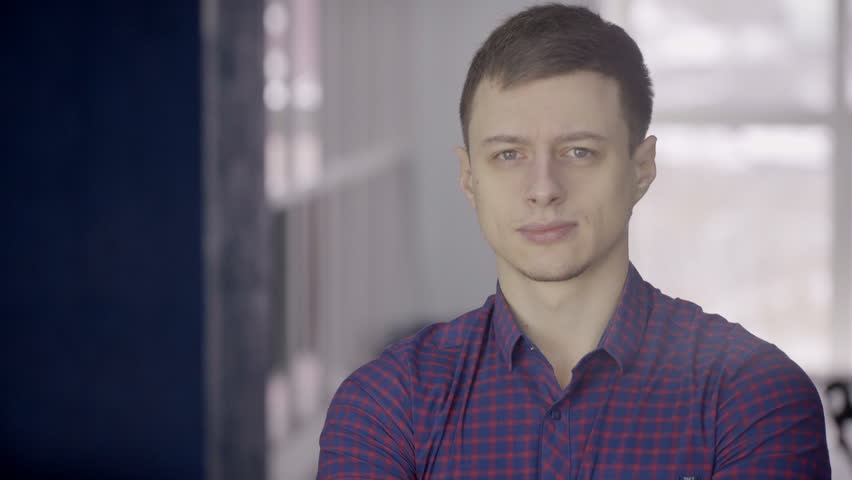Portrait of a young European man in a blue checkered shirt. An adult male character with a short haircut, which looks straight and a little screw up his eyes.