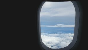 4K. aerial view through an airplane window. beautiful white clouds in blue sky background. traveling by air.