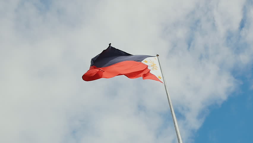 Flying bicolor flag of the Philippines with central golden sun representing the provinces and stars the islands.