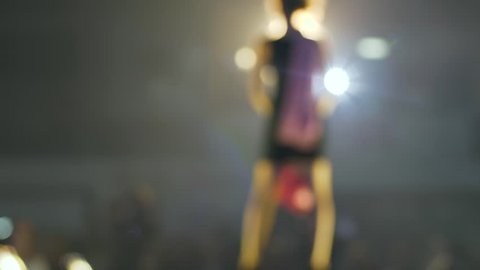 fashion show, models on high heels are walking along catwalk on unfocused background