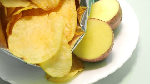 Homemade potato chips. Fast food. Popular junk food. Potato tubers and chips rotate smoothly on bamboo napkin. Diabetic diet.