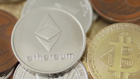 A hand putting an Ethereum coin on a pile of different cryptocurrency coins