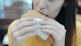 Closeup of girl enjoying a fresh hamburger. Female mouth with painted lips making a bite from baked pastry. Food advertisement