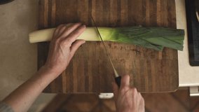 Woman cuts a leek into two halves of a video