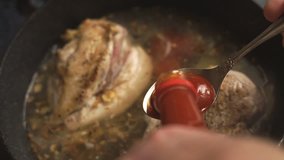 Hot chili sauce is poured into chicken breasts in a saucepan 
