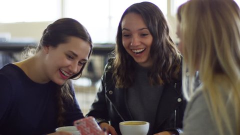 Friends Hang Out At Coffee Shop, Blonde Woman Shows Her Friend's Something Really Funny On Her Smartphone, They Laugh -  Shot On Red Scarlet-W Dragon In 4K/Slow Motion