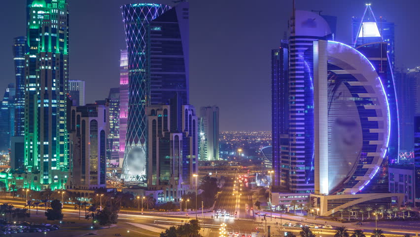 The skyline of the West Bay area from top in Doha timelapse, Qatar. Illuminated modern skyscrapers aerial view from rooftop at night. Traffic on the road