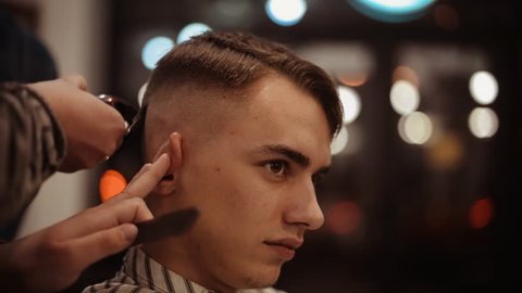Male haircut with electric razor. Close up of man hair cut. Male hands barber shaving man with electric razor in barbershop. Barber cutting hair with hair trimmer.