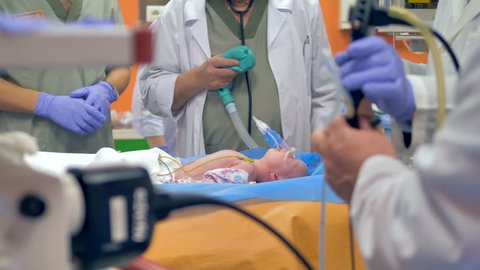 Doctors carrying out a medical procedure on a unrecognizable baby. 4K.