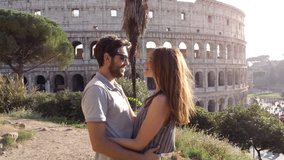 Happy young couple tourists taking selfie video in front of colosseum in rome at sunset with smiling having fun camera point of view pov