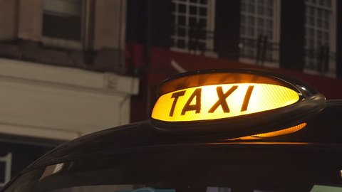 A taxi sign on a black cab. London at night.