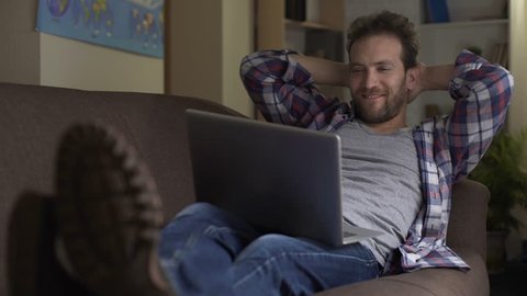 Tipsy man watching video on laptop, smiling and falling asleep, idle lifestyle