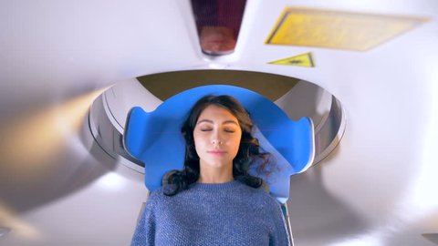 Hospital emergency MRI image scan. Woman lays in Magnetic Resonance Image device during medical exam. 4K.