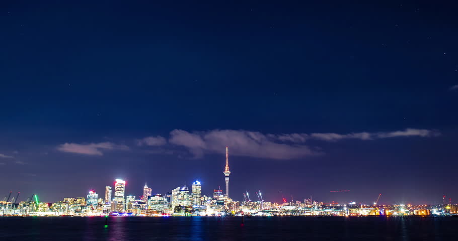 Time lapse of a starry sky above Auckland city’s skyline with the harbour, the ocean and some boats at the front