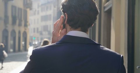 In the city, a businessman answers the phone, send messages and smiles for the beautiful job news. Concept: technology, telephony, business trips, business.