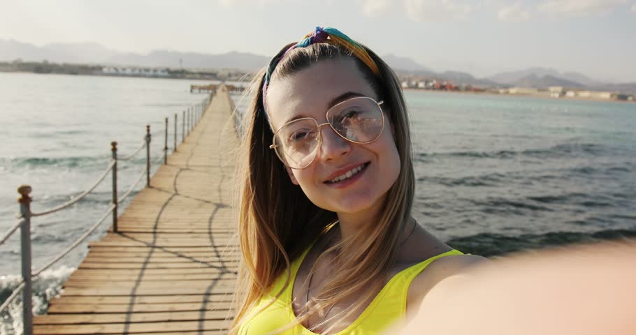 Close up of young woman with glasses take sellfie waving hand smiling  