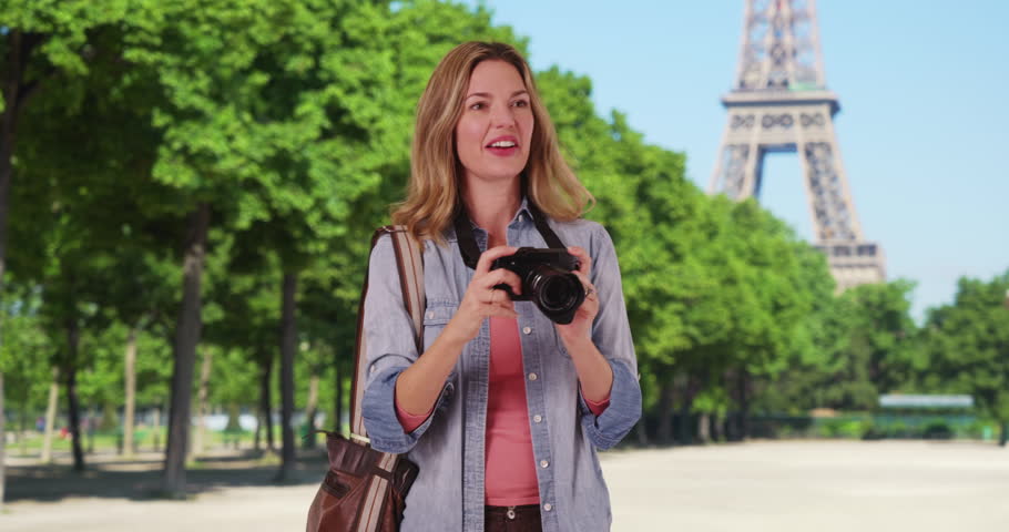 Travel photographer in Paris taking a picture outside smiling. Paris woman tourist taking photograph of summer vacation. 4k