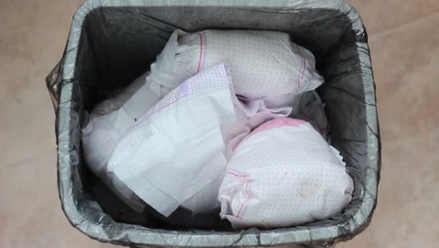 Diapers in grey garbage cart. Waste sorting. Disposing of poopy diapers. Mom throws dirty diapers in the trash bin