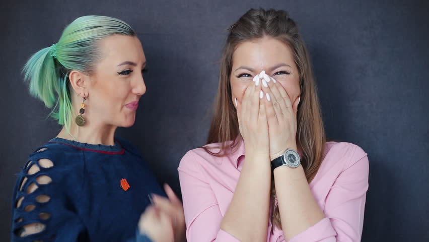 Two beautiful girl sharing secret information with shocked surprised telling interesting funny news on a gray background | Shutterstock HD Video #1007463475