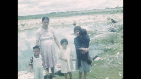 1940s: Mexican family stands by a pond. Women kneel next to pond doing laundry. State limit sign leaving Jalisco and entering Zacatecas. Open road driving on rural roads with stone sides.