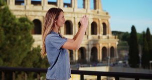 Smiling tourist recording video of summer vacation in Rome. Happy attractive female near the Coliseum takes picture with her cellphone. 4k