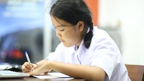 Asian elementary school student doing homework, Asian young lady sitting in living room and using computer searching data, video for education and family life concept