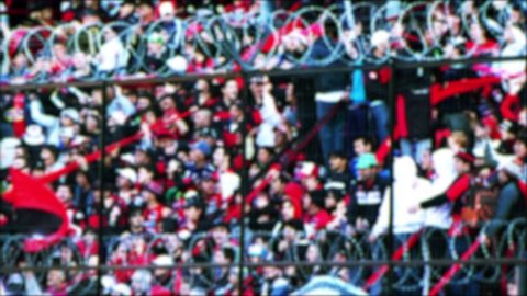 Blurred Crowd of Fans known as Barra Brava cheer on their Team during the Game on a Tribune at a Soccer Stadium in Argentina. 