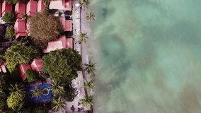 Top view of black volcanic beach with waves of ocean on clean shore with houses for summer vacation. Video. Aerial scenery shooting of beautiful sea with azure water and waves