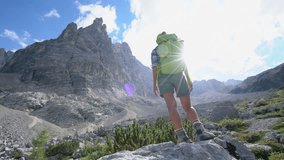 Climber female on top of mountain celebrates achievement, shot in 4K resolution in the Dolomites mountains, Italy. Beautiful peaks on background, summer season. People travel success freedom concept
