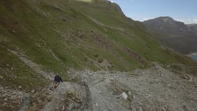 Drone shot of a young man hiker sitting on top of a ridge in Switzerland, 360 degrees view, mountains and lake. People nature outdoor activity concept
