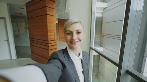 POV of young businesswoman in suit taking a selfie photo holding smartphone and have fun in modern office