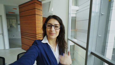 POV of young businesswoman in suit taking a selfie photo holding smartphone and have fun in modern office
