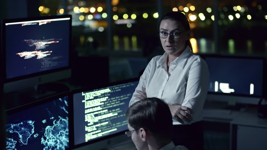 Tilt up of female cyber security professional talking to male colleagues while having meeting in dark office at night | Shutterstock HD Video #1007495218
