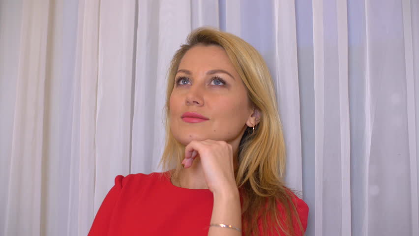 Portrait beautiful woman thinking looking up. Face blond woman in red dress