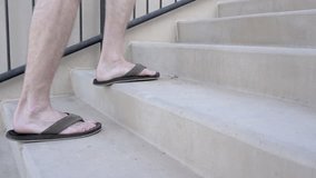Slow Motion Low, Side Angle Video of Male Feet Wearing Flip Flops Walking up Stairs