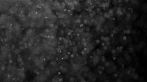 Falling White Particles. Small white particles flow in the air on a black background to simulate snow, blizzard, or a microcosm of the Christmas magic. Filmed at a speed of 120fps